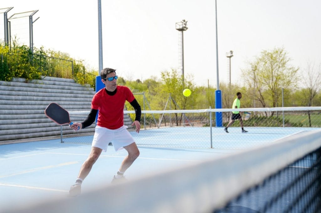 Focused player prepares for a forehand shot during an outdoor pickleball match.