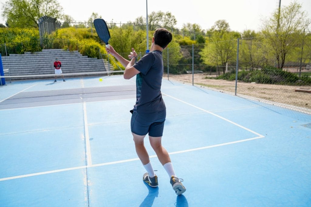 Pickleball player striking the ball on a blue court during an intense outdoor match